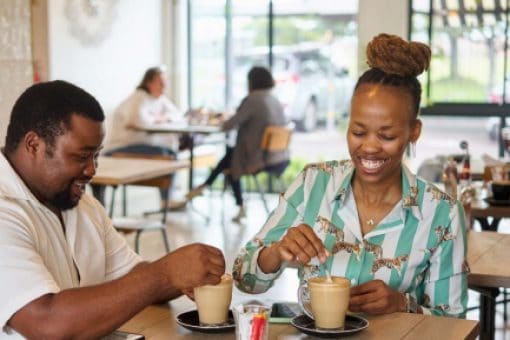 Two people sitting together at a café, enjoying coffee and smiling.
