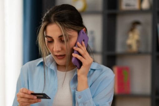 Woman holding a credit card while talking on her smartphone.