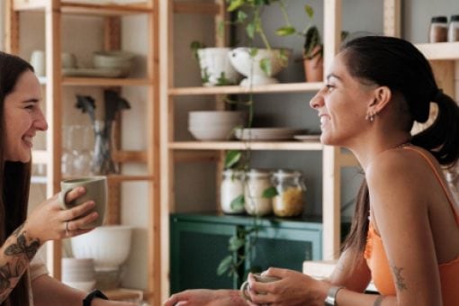 Two women sit together talking in a cafe.