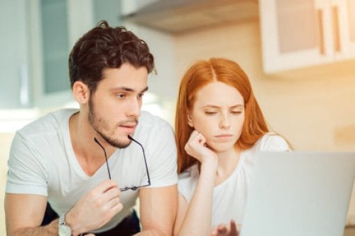 A couple sits together looking at a laptop computer.