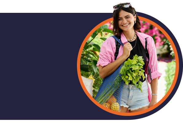 Woman in pink shirt carrying a reusable shopping bag filled with produce