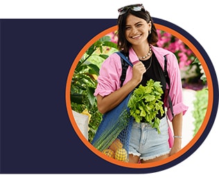 Woman in pink shirt carrying a reusable shopping bag filled with produce