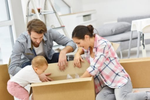 Young couple and baby reach into box as they move into new home