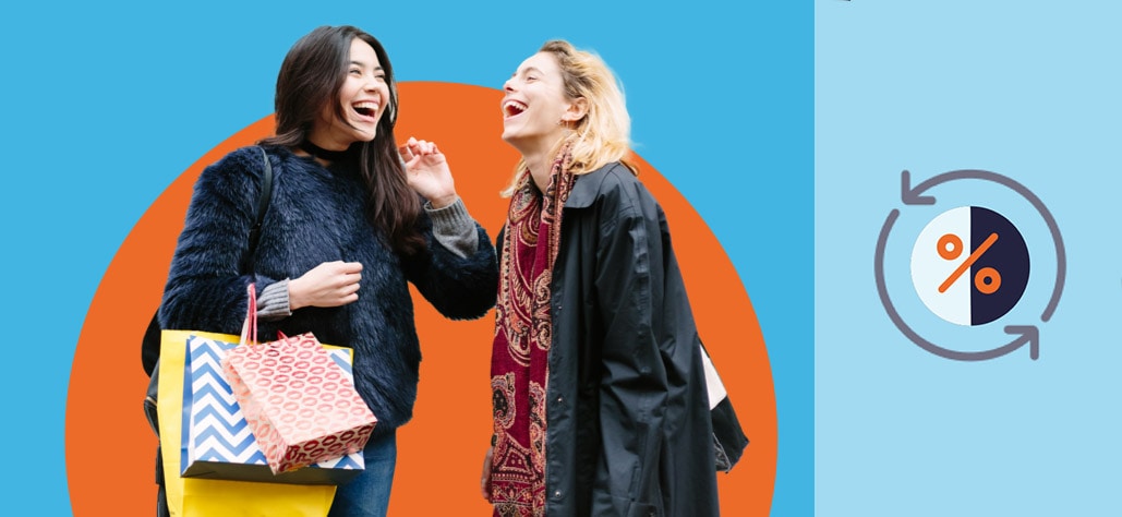 Two women laugh together as one of them holds shopping bags in her hand