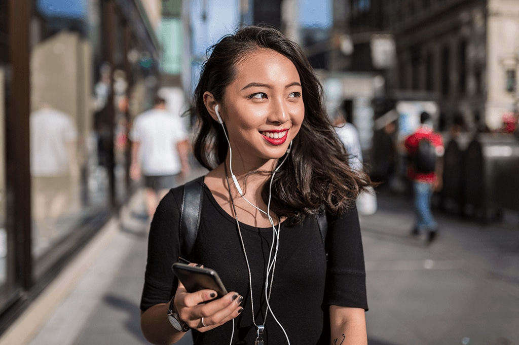 young woman walking and listening to music through headphones