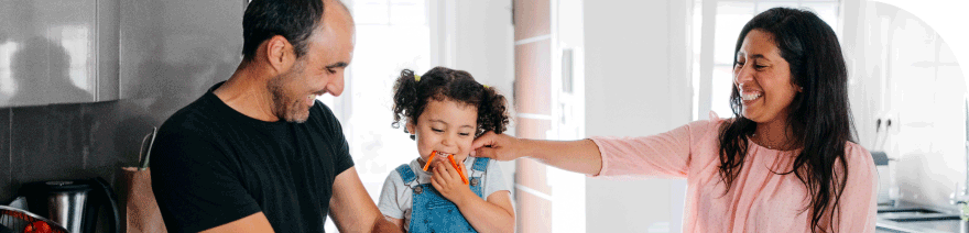 Parents with their young child in the kitchen, all smiling and interacting