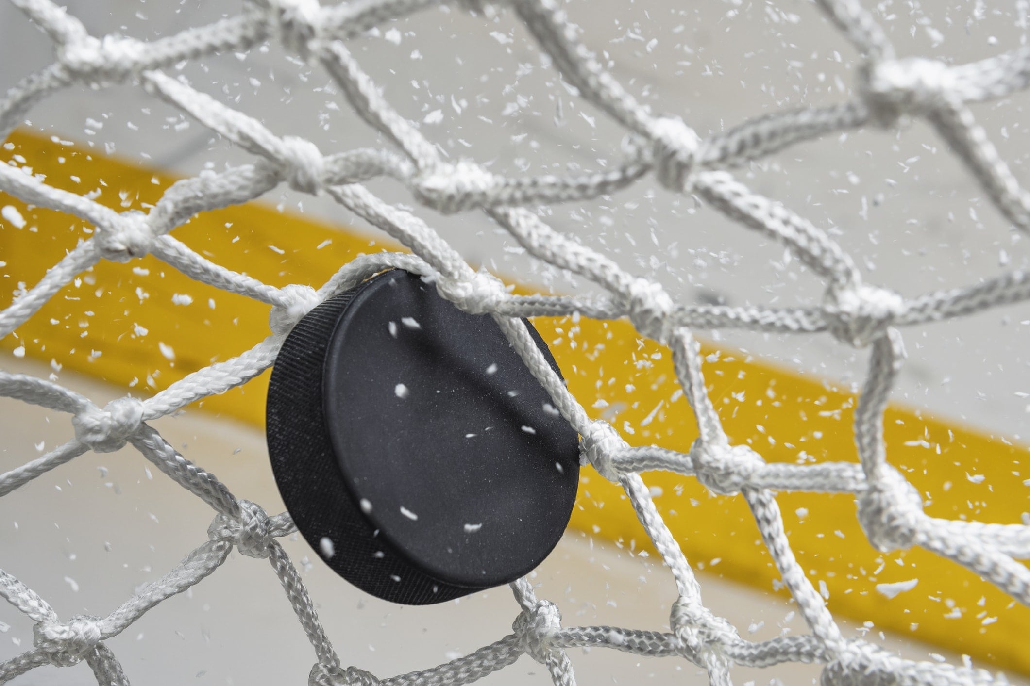 hockey puck hitting white hockey net