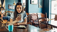 Young woman smiles while looking at mobile phone.
