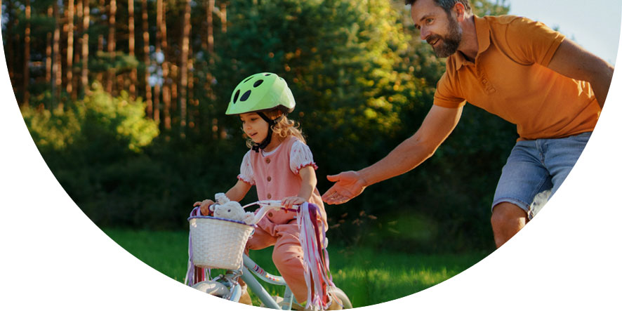 Image of a father helping daughter learn to ride a bike