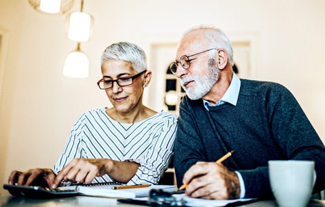 Image of a couple with a calculator and notebooks working on their finances