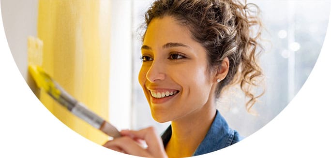 Image of a woman painting a wall with a brush