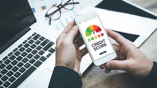 A close-up of two hands holding a phone while the person checks their credit score..