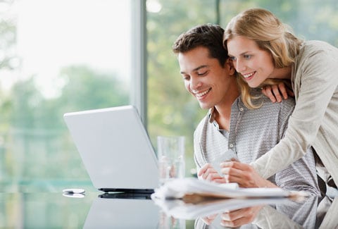Man and woman smiling while looking at computer together