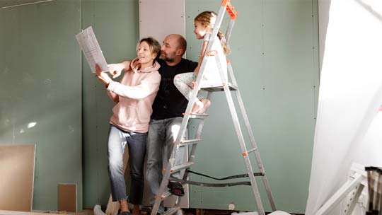 A couple and their young child look at plans for a renovation.