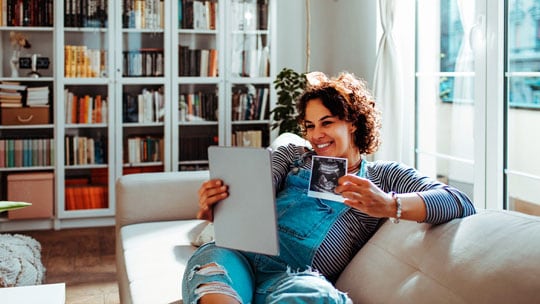 Woman showing her sonogram image to a video call.