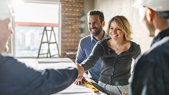 Man and woman shake hands with contractor on their home remodel project