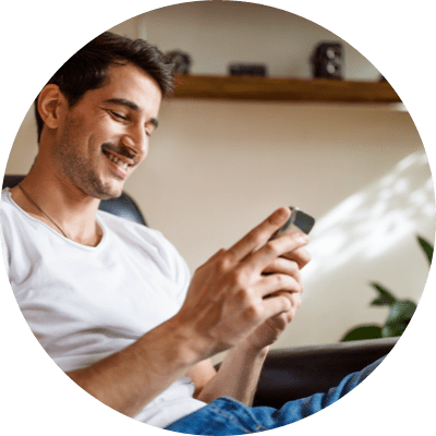 A man sitting and smiling while looking at his phone