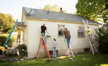 Group of 5 people painting the outside of a house.