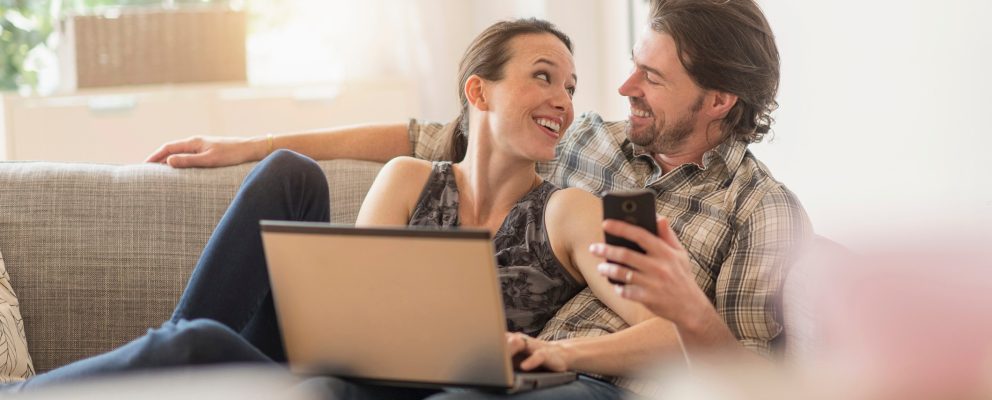 Couple looks at each other as they sit on the couch.