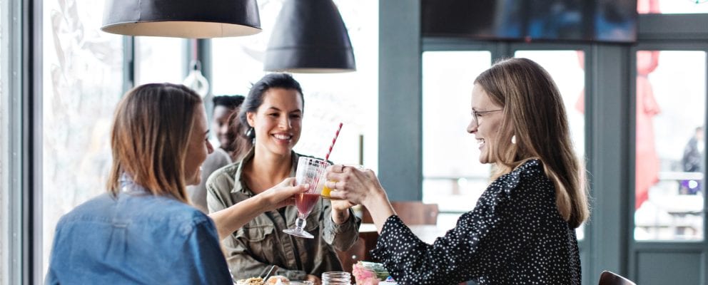 Three women toasting with various juice drinks.