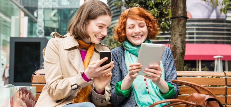 Two women look at their smart devices.