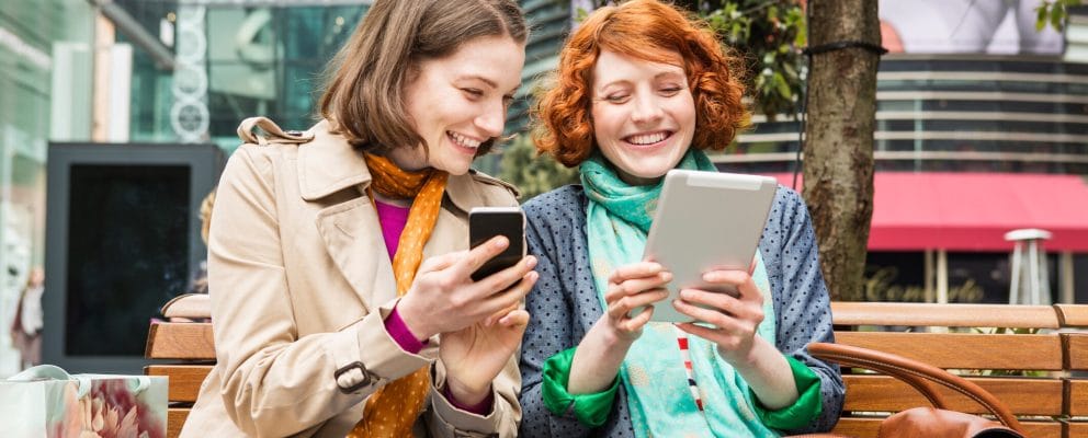 Two women look at their smart devices.