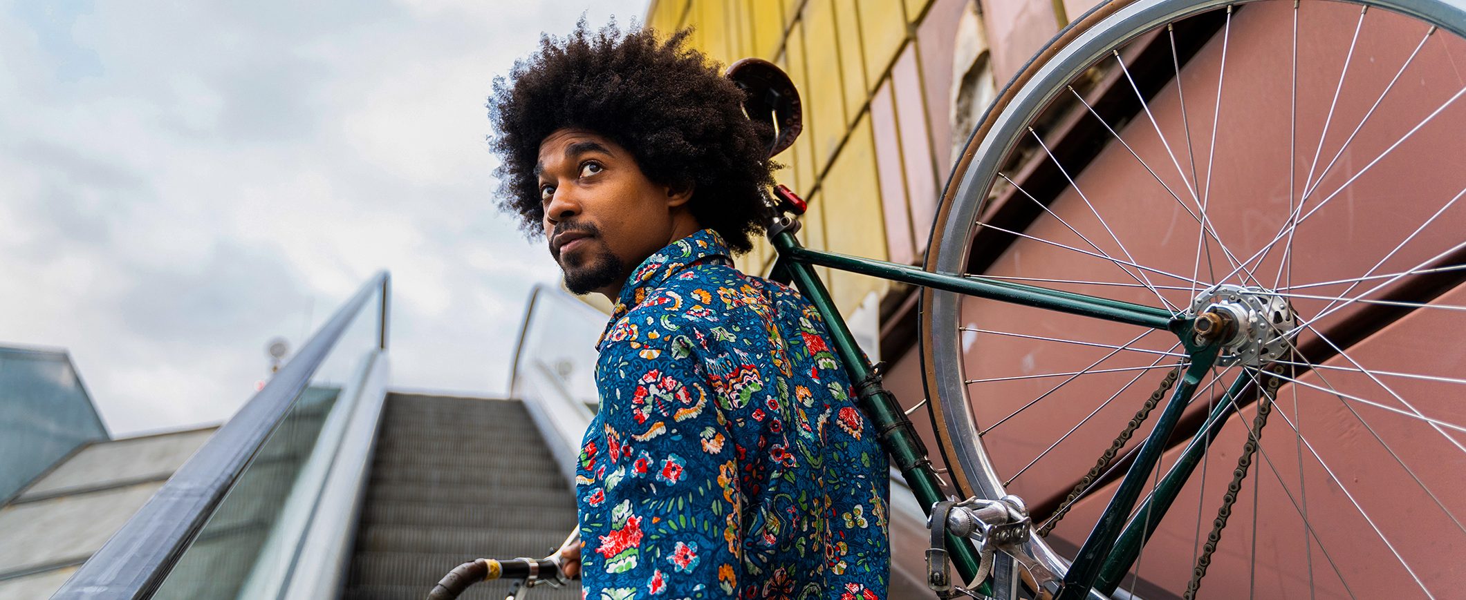 A man carries his bicycle up a flight of stairs.