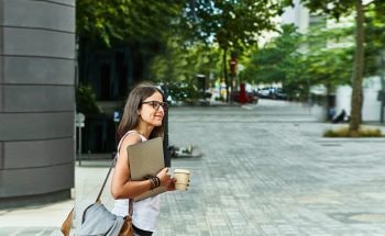 Woman carrying her laptop looks both ways before crossing the street.