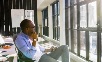 Man sitting in an office chair looking out the window.
