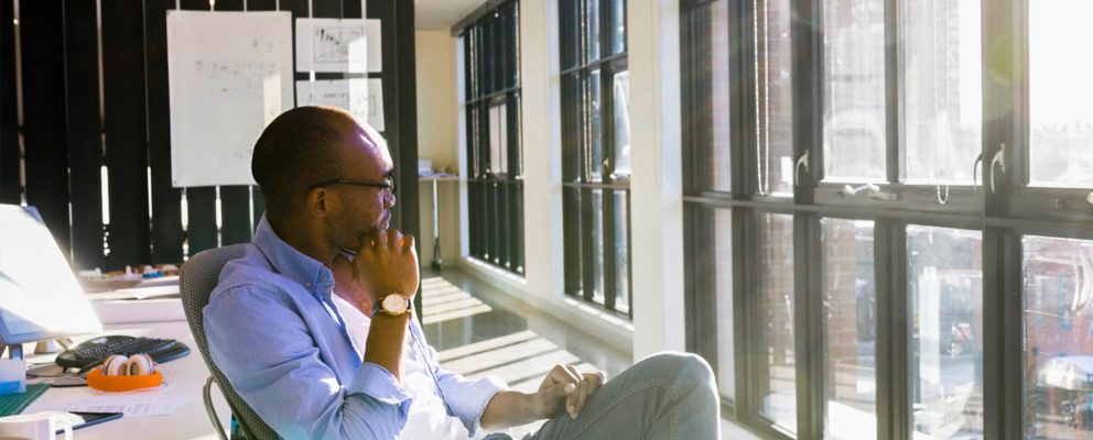 Man sitting in an office chair looking out the window.