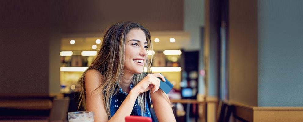 Lady holding a payment card and smiling.