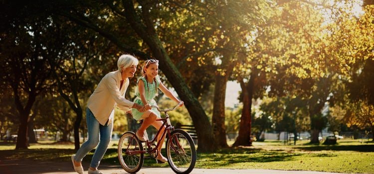 Woman helps her granddaughter ride a bike.