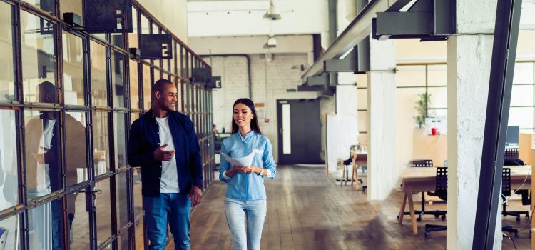 A man and woman walk through an office