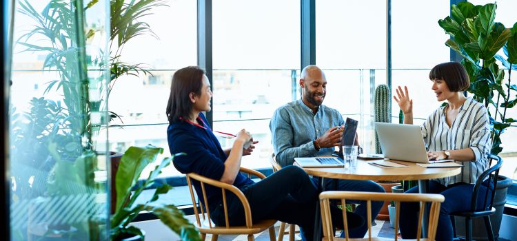 Two men and a woman sit at an office table with computers.