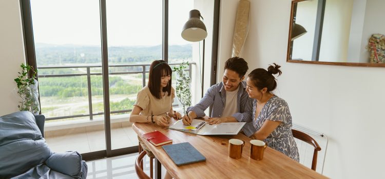 3 people sit at a dining room table and look over documents.