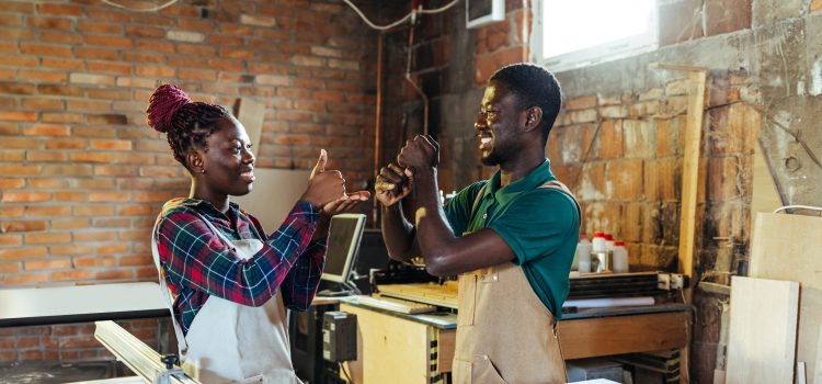 A man and woman use sign language in their workshop.
