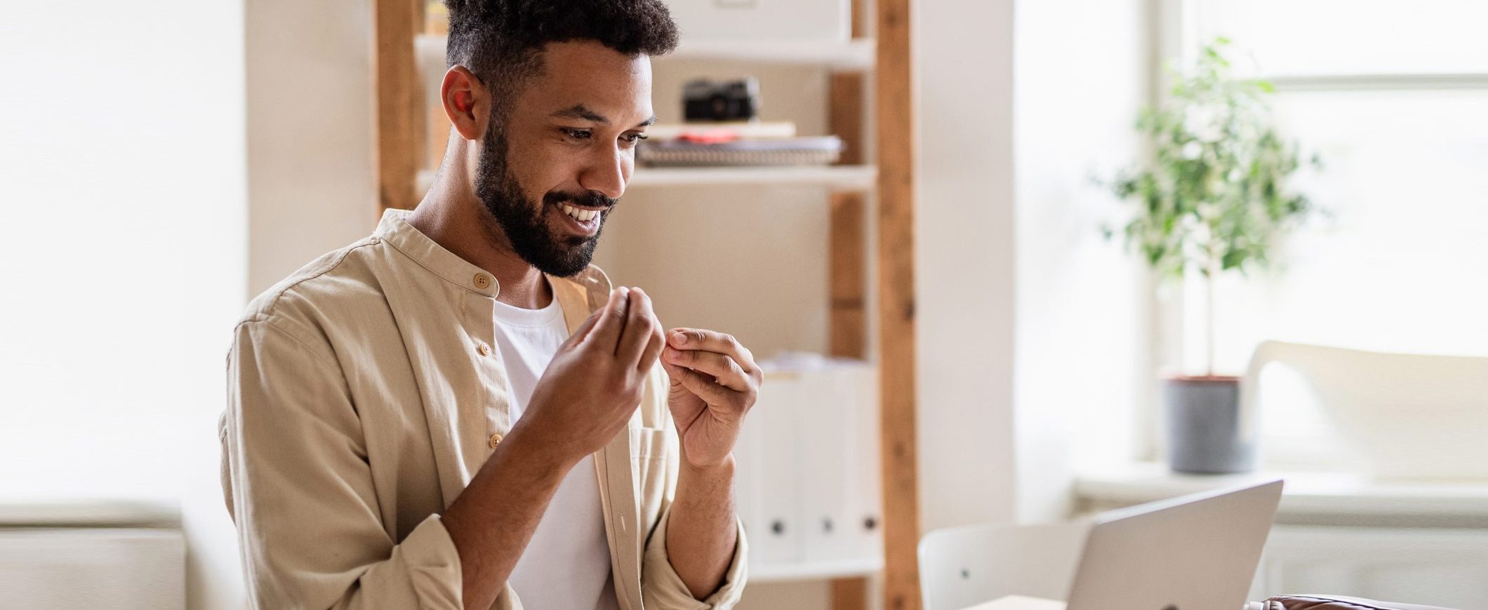 A young man uses sign language while on a video call.