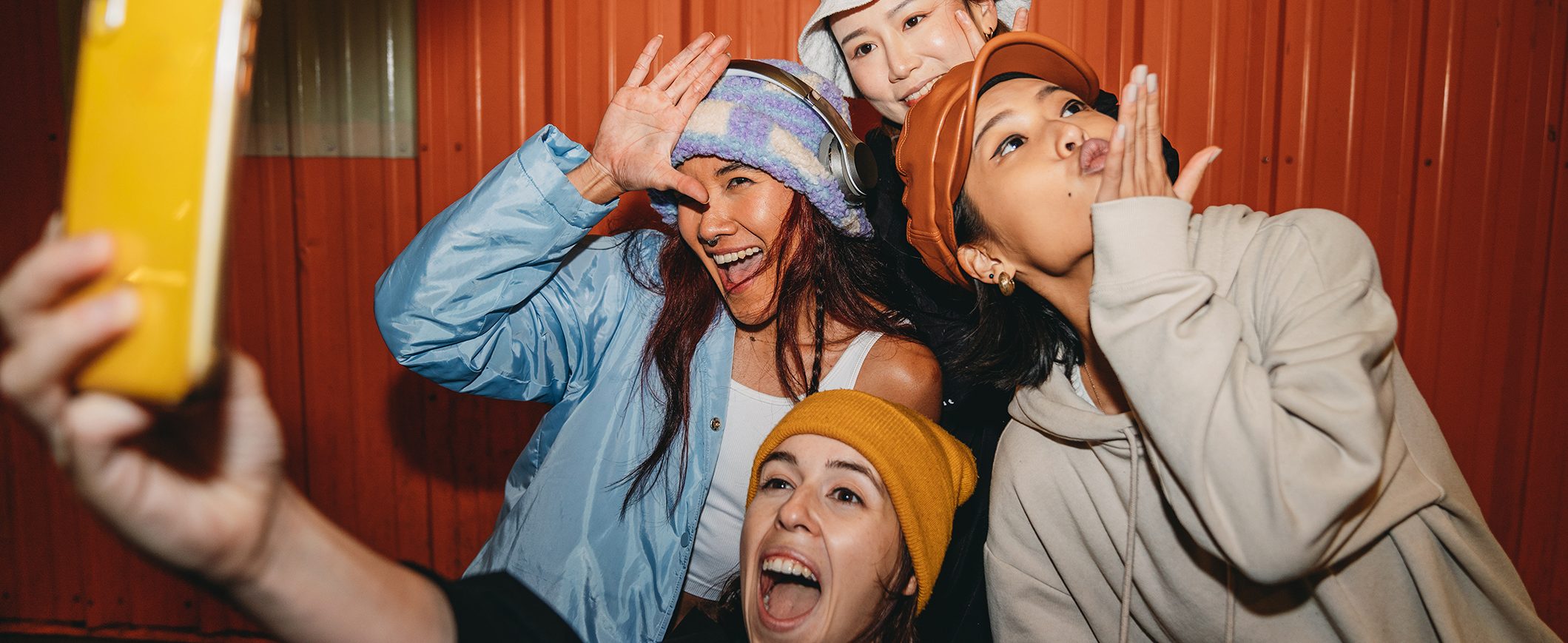 Four young women laugh together and take selfies. 