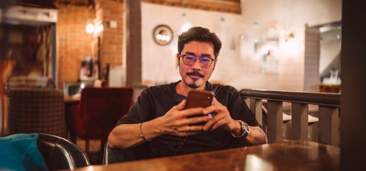 A young man sits and looks at his phone.