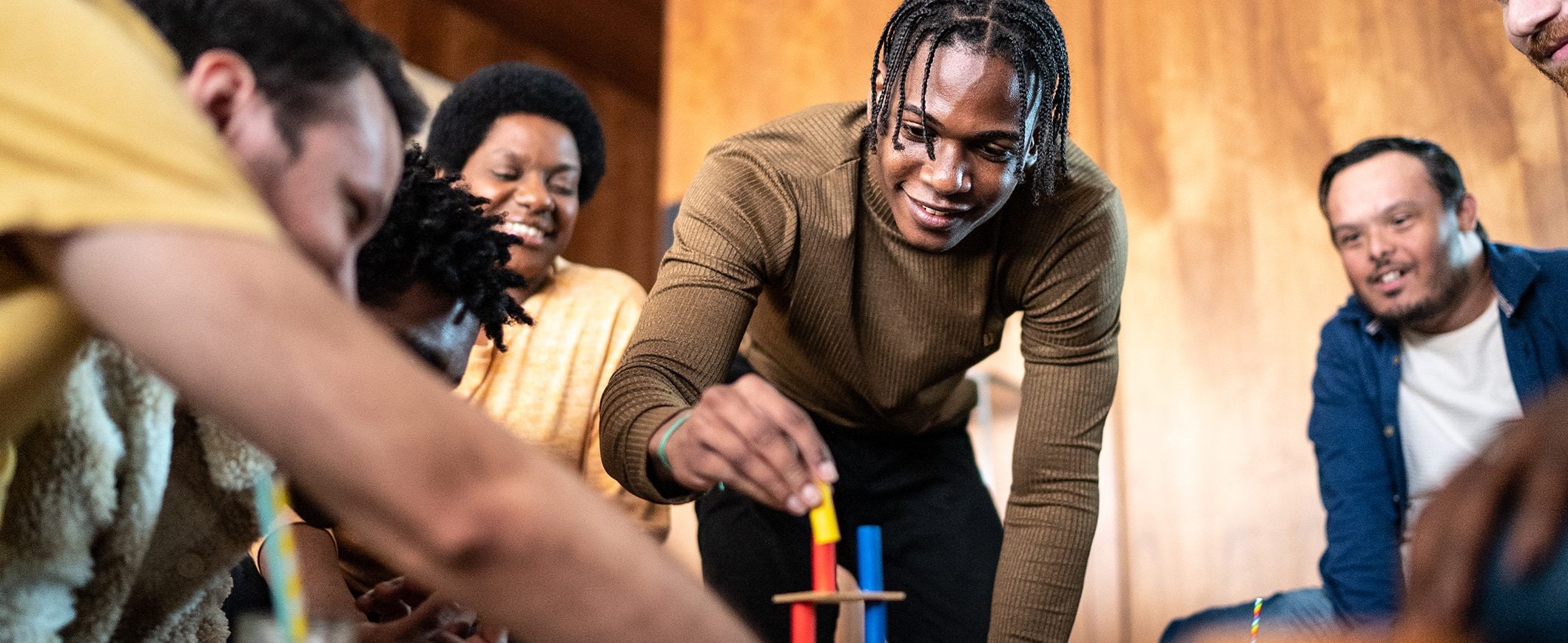 A group of friends gathers around a table, playing a game at a party.