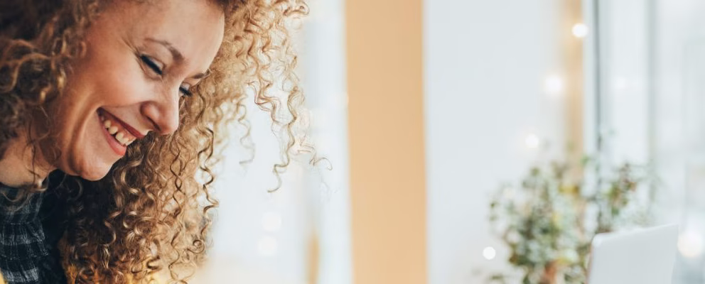 A close up of a woman reading her credit card to input the card number on her laptop keyboard.