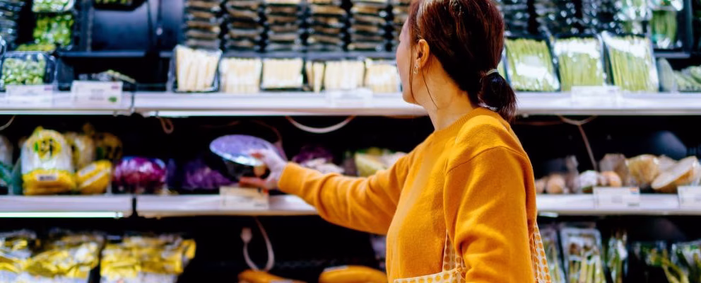 A woman chooses items from the produce section of a supermarket.