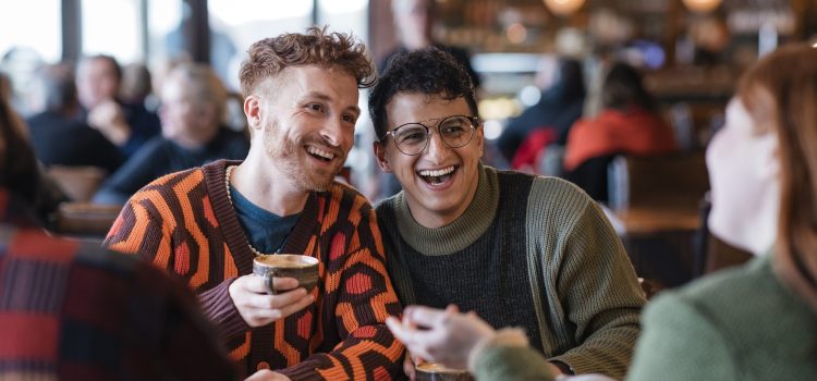 Two young men chat with friends in a crowded café.