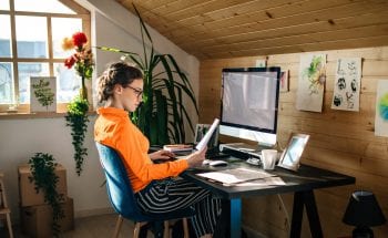 A woman looks at a piece of paper while working at her desk
