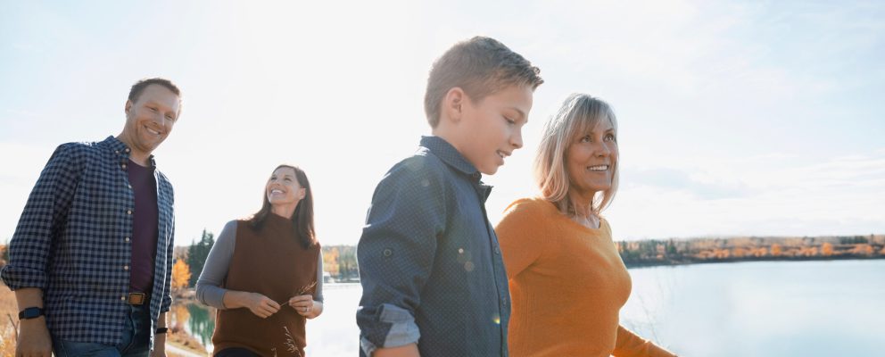 Four people walking and talking by the water.
