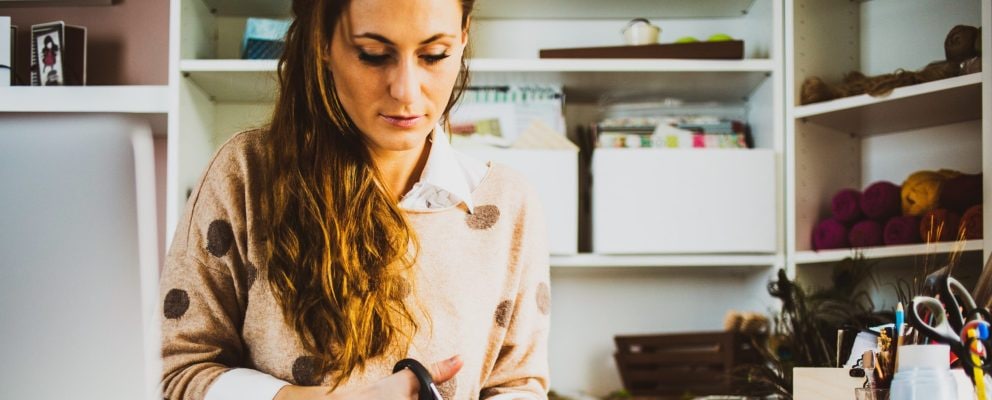 A woman sits at her desk cutting paper