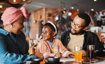 A family eats breakfast while the daughter smiles at her mother and father