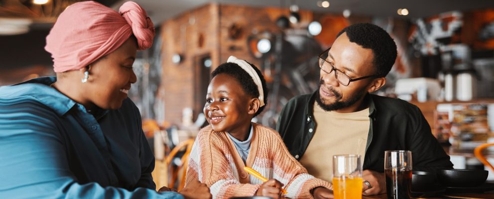 A family eats breakfast while the daughter smiles at her mother and father