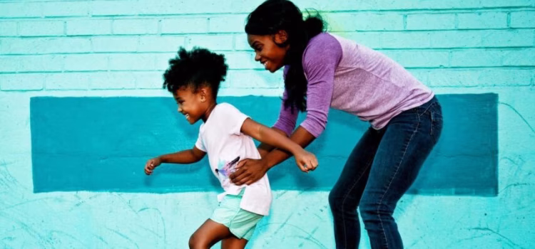 Woman helping her daughter learn how to roller skate.